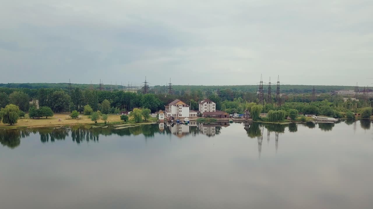 approximation to houses near the riverbank on the background of forest and high-voltage lines