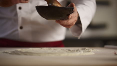 chef cooking italian pizza on wooden board. man hands spreading tomato sauce.