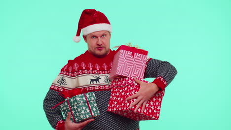 Lovely-man-in-Christmas-red-sweater-hat-presenting-Christmas-gift-boxes-stretches-out-hand-to-camera