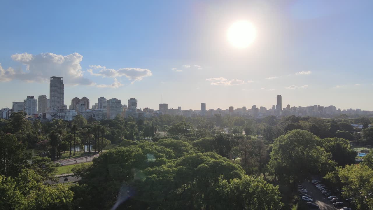 dolly aéreo volando sobre los bosques de palermo con edificios al fondo durante el día, buenos aires