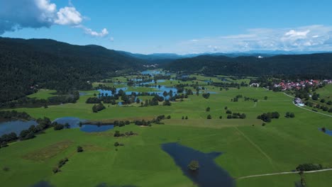 aerial panorama view showing intermittent lake named cerknica surrounded by green mountain landscape with blue sky in summer - slovenia