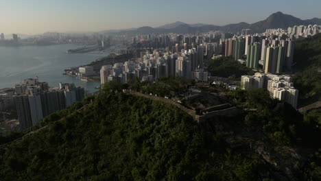 orbiting shot of devil's peak with victoria harbour, kowloon bay and mountain range in backdrop during golden hour, hong kong