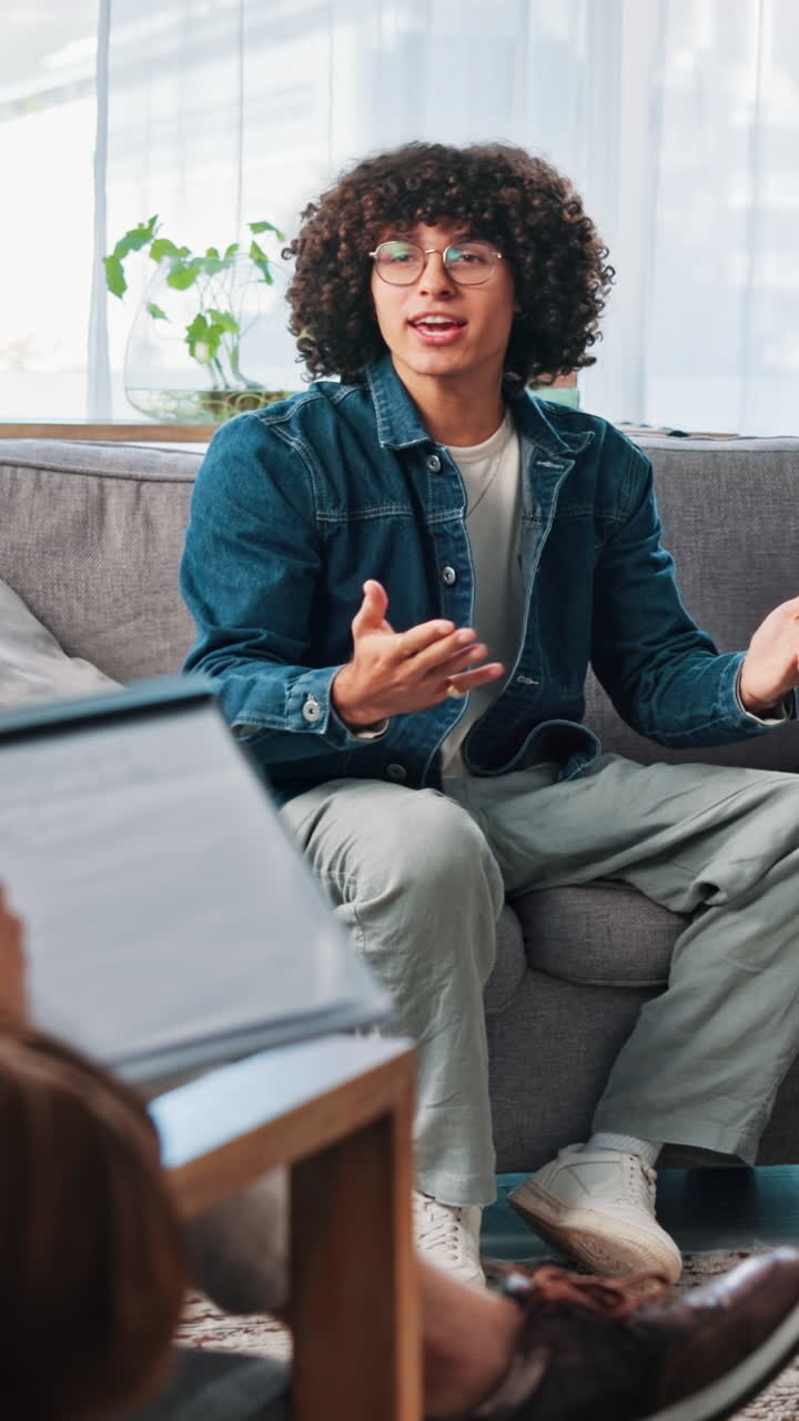 Young Man with Curly Hair Talking and Gesturing on Couch