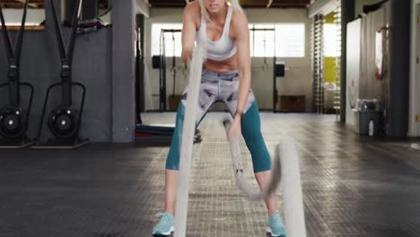 front view of an athletic caucasian woman working out with battle ropes