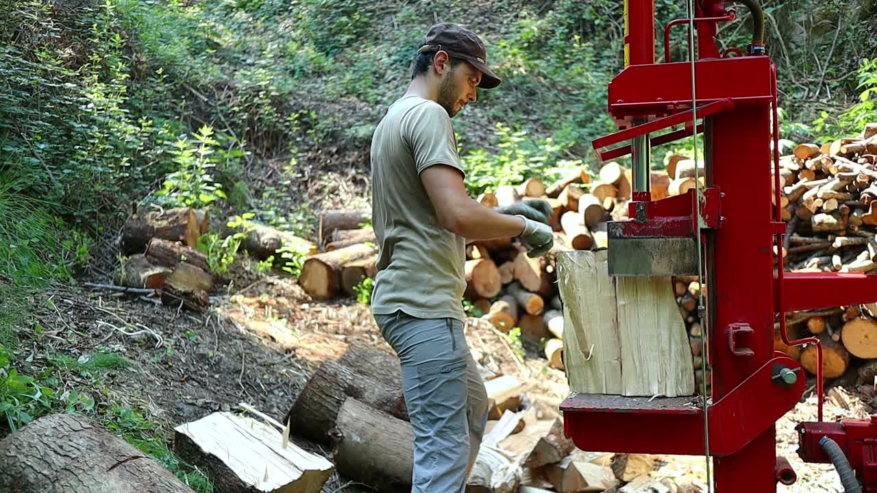 Un uomo usa una spaccalegna per spaccare tronchi di legno fresco.
