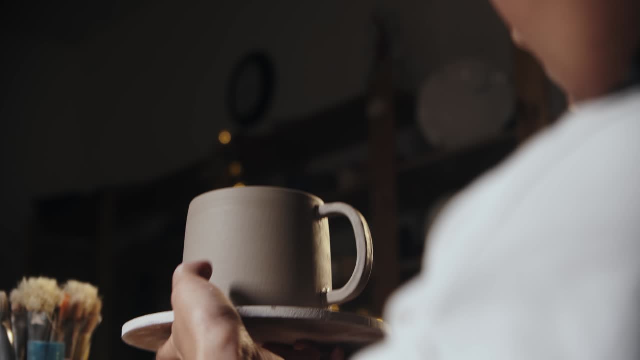 joven alfarera atando un mango a una copa de arcilla