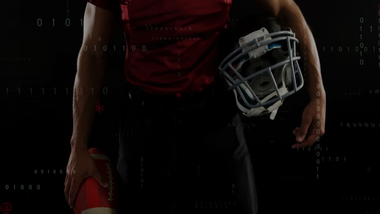 Giocatore di football americano in piedi in uno studio tecnologico buio, che tiene in mano casco e pallone da football con codice binario animato.