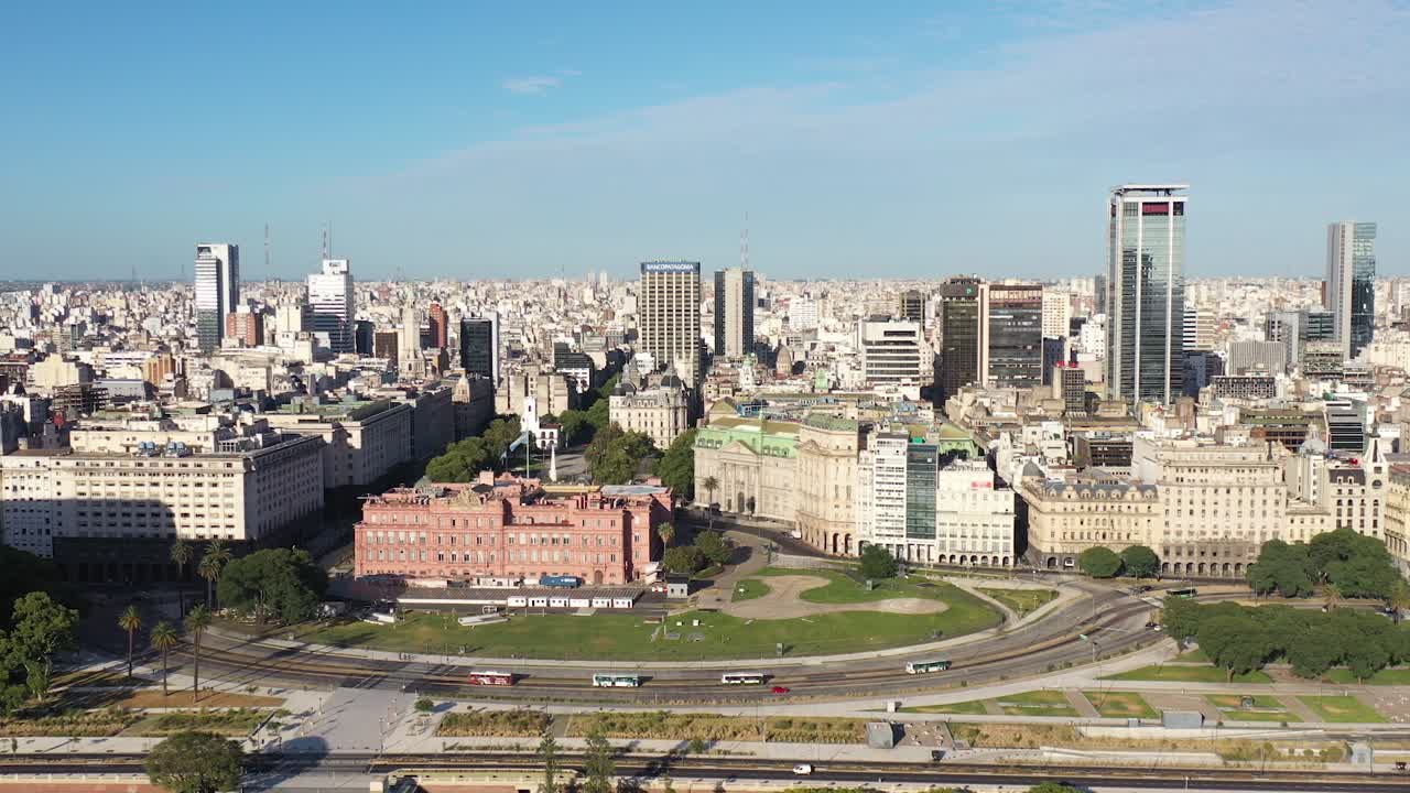 An aerial view of Buenos Aires' Plaza de Mayo, the iconic Casa Rosada, and the city's skyline, under the clear sky