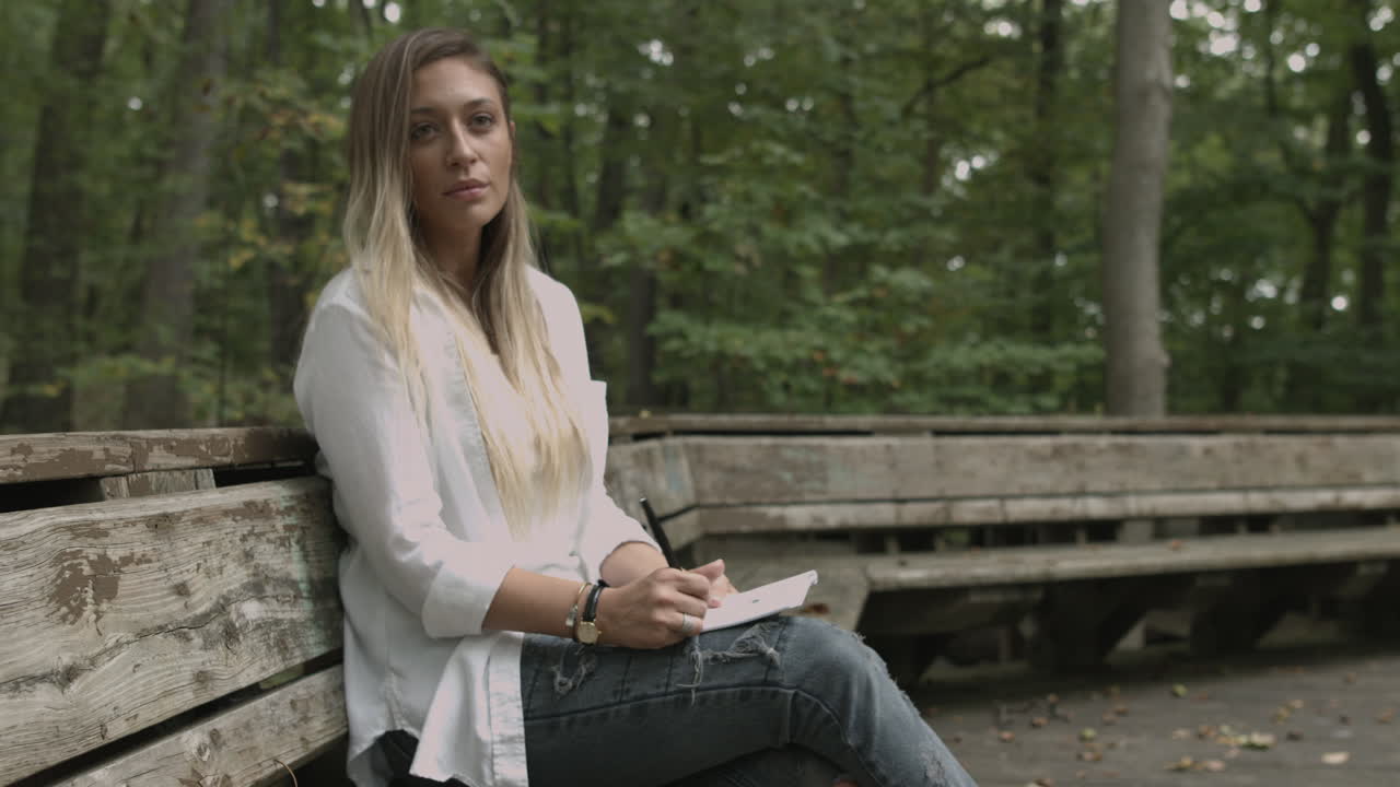 돌리 슬라이더 여자는 숲 숲 환경에서 노트 패드 그림에 씁니다.