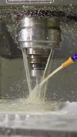 active cnc machine tool with cooling liquid stream and metal shavings during operation