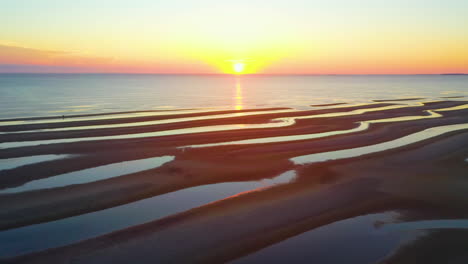 cape cod bay epic sun set aerial pan right drone footage of beach at low tide with people walking, sand bars and puddles