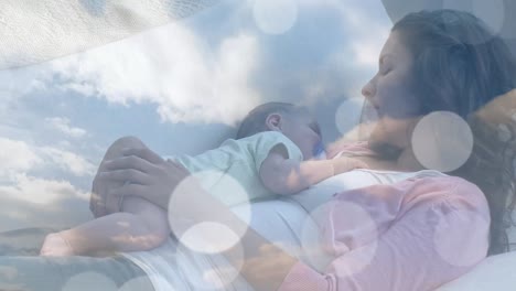 animation of clouds over caucasian mother sleeping with her baby