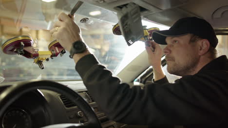 repairman fastens suction cups to replace cracked windshield, side view