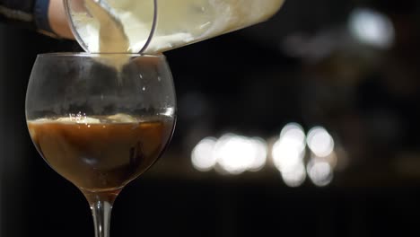 hand pours fresh whipped cream into glass with coffee