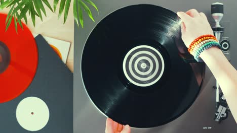 turntable vinyl record player on a wooden table. red plate. included gramophone and torque plate closeup. hand girl with a bright accessory puts needle on vinyl record