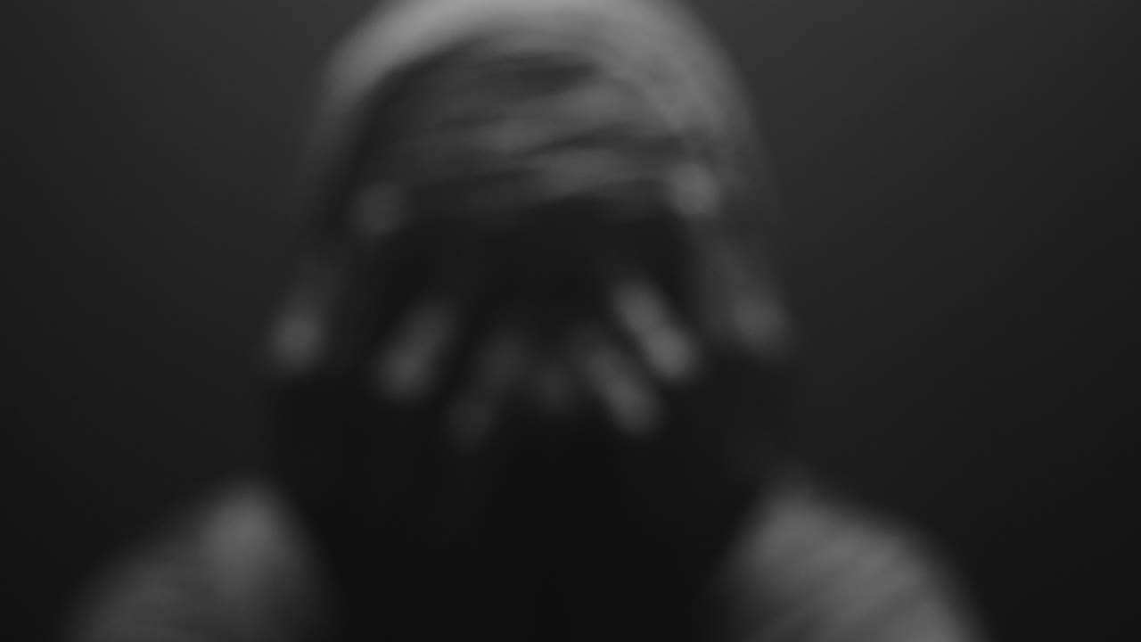 A mummified woman against the dark background in keeps her hands on her face the powerful pose full of despair