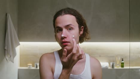 hombre aplicando crema facial en el baño
