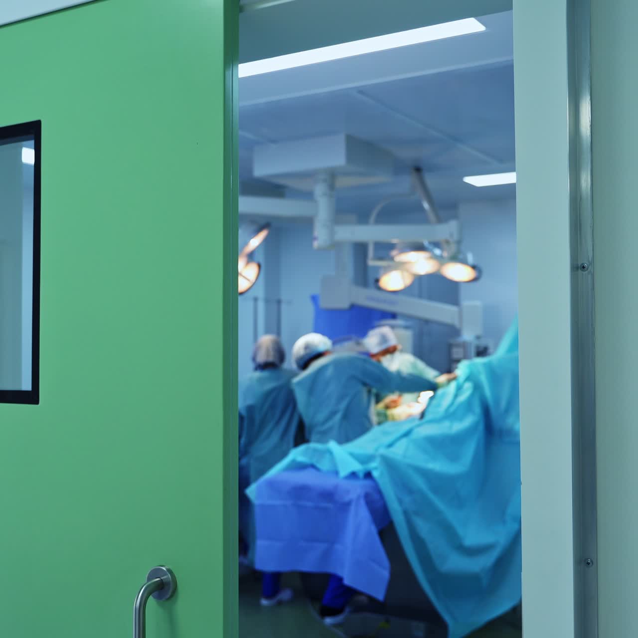 Medical team performing surgery in the big modern operational room with advanced equipment. Footage moving from the surgery room into hall
