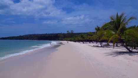 tropical hut on white sand beach meeting calm turquoise water in koh rong island, cambodia. spectacular aerial view flight overflight flyover drone