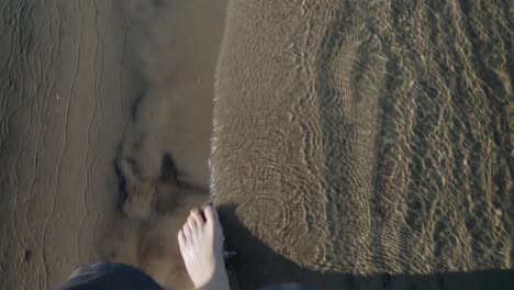 top view of female legs walking along shoreline