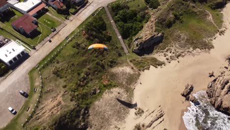 Turista-Disfrutando-Del-Parapente-Desde-Los-Acantilados-Junto-A-La-Playa-En-El-Pueblo-De-La-Pedrera-En-La-Costa-Atlántica,-Uruguay