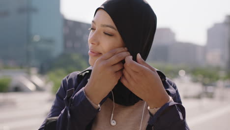 Retrato-En-Cámara-Lenta-De-Una-Hermosa-Mujer-Musulmana-De-Raza-Mixta-Que-Disfruta-Escuchando-Música-Se-Quita-Los-Auriculares-Sonriendo-Feliz-En-El-Fondo-Urbano-De-La-Ciudad