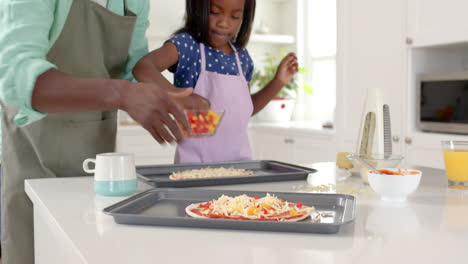 african american, father and daughter making homemade pizza together in bright kitchen