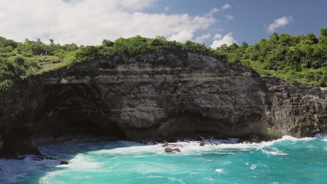 Dramatic rocky coastline with a large sea grotto on the tropical island of Nusa Penida