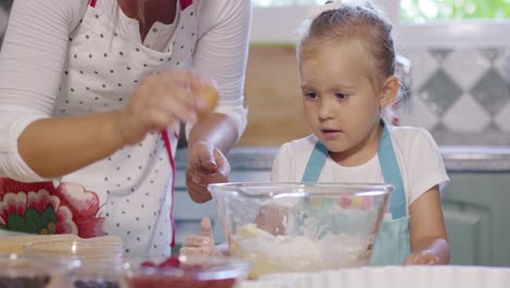 Attractive-little-girl-watching-her-mother-baking