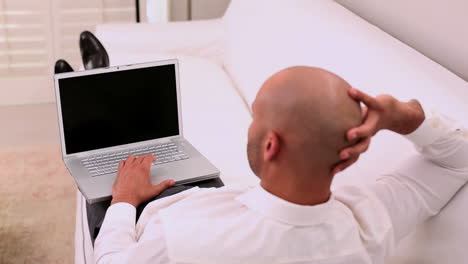 relaxed businessman sitting on couch with laptop
