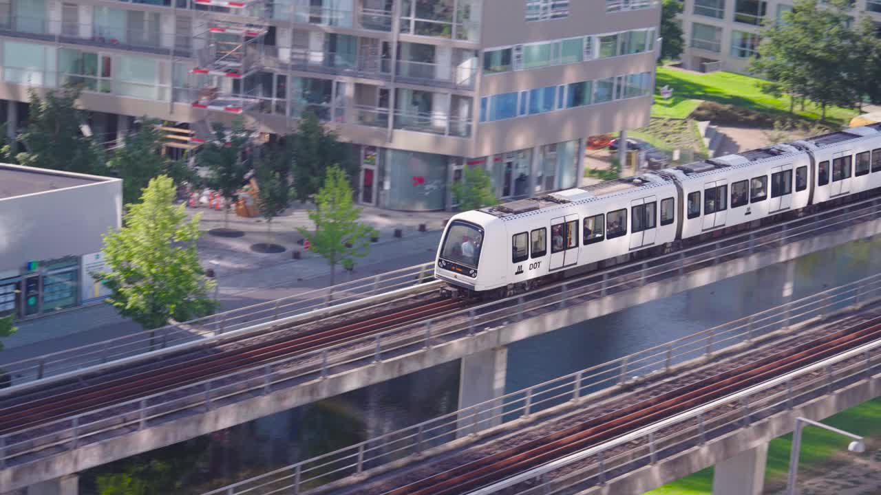 Train drive on Orestad metro line concrete viaduct near buildings, Copenhagen