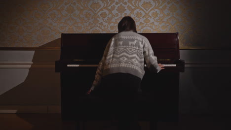 woman playing piano in a dark room