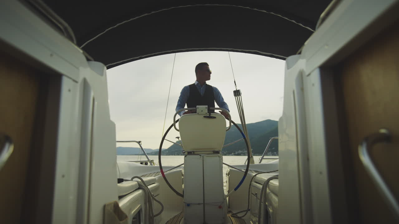 hombre dirigiendo un yate al atardecer