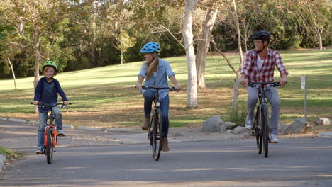 parents and son cycling towards camera in a park