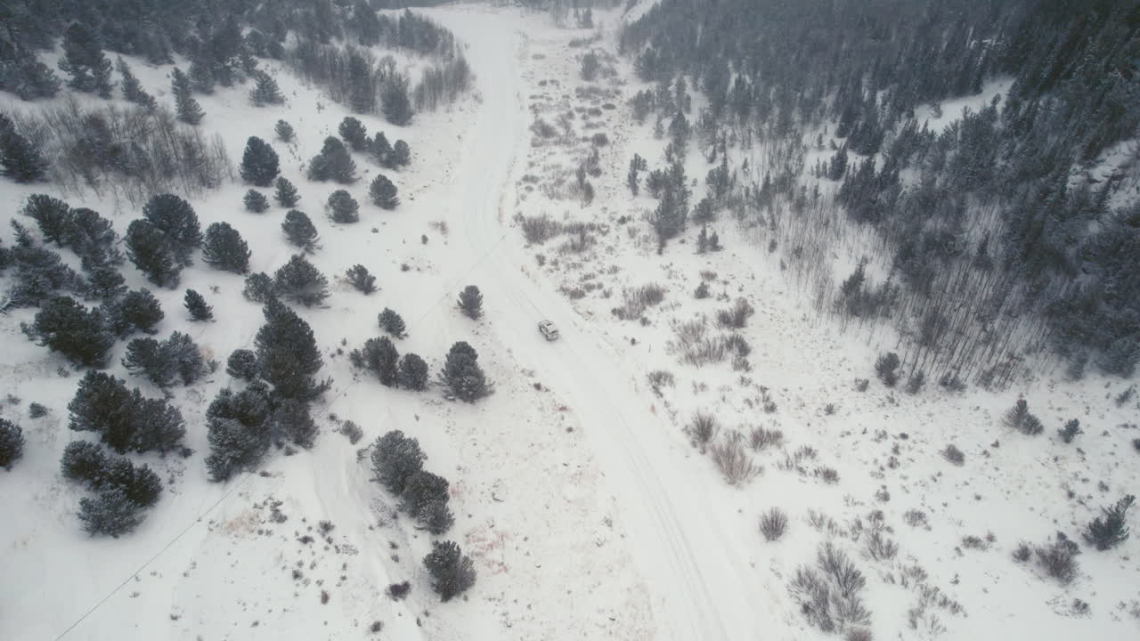 vista aérea de drones de land rover defender d90 suv estacionado en un camino cubierto de nieve en el camino del bosque alpino en las montañas rocosas cerca de nederland boulder colorado usa durante las fuertes nevadas