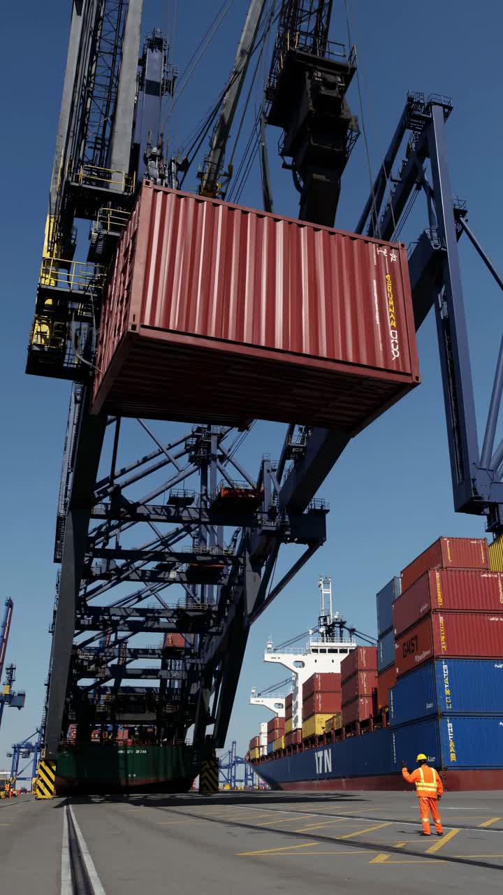 Low-angle shot of a massive crane loading containers onto a cargo ship, capturing the industrial