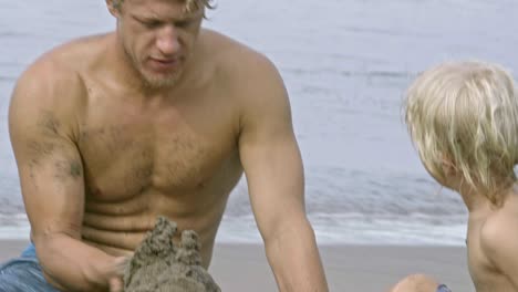 dad and little son building sandcastle at ocean beach