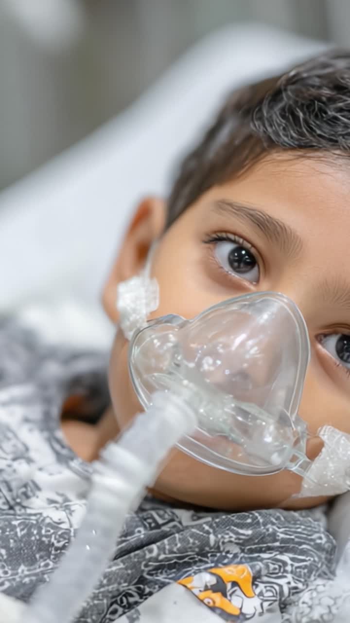 Un Bambino Che Riceve Cure Mediche con una Maschera d'Ossigeno in un Contesto Ospedaliero, Focalizzato sull'Espressione Tenera e sull'Importanza dell'Assistenza Sanitaria per i Bambini
