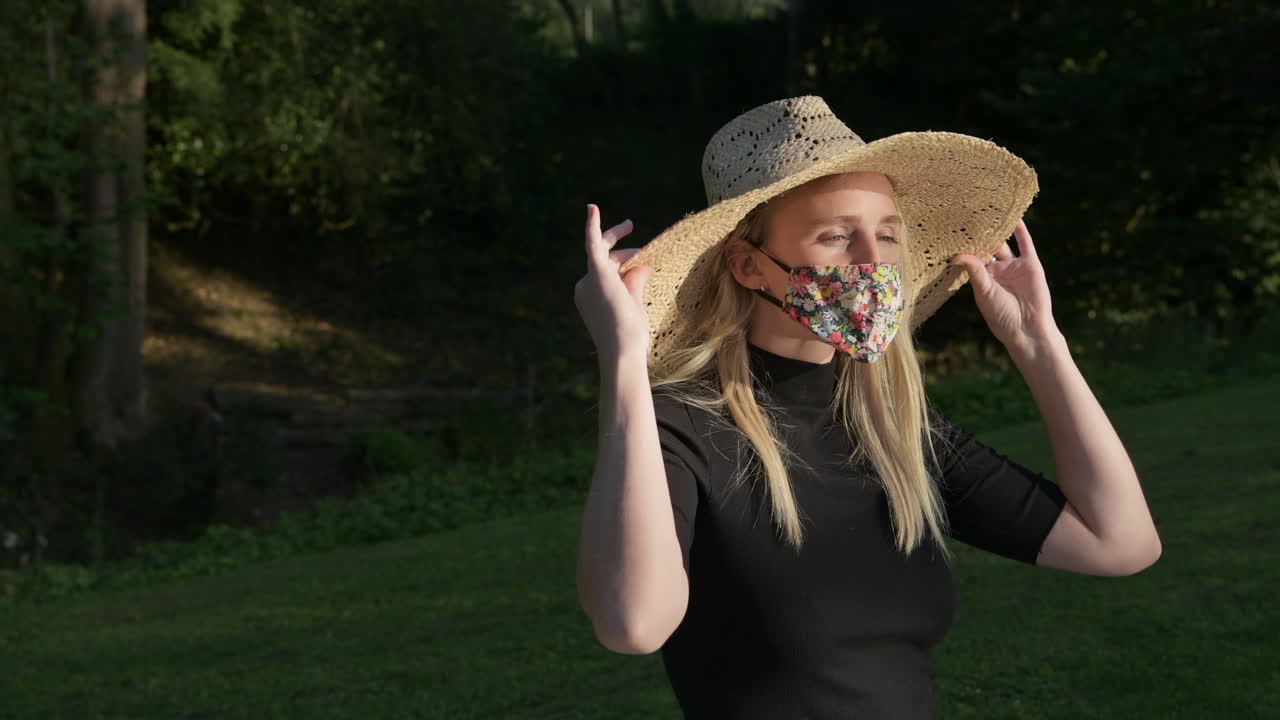 A medium shot of a beautiful young woman taking off her face mask outdoors