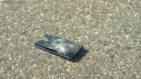 vehicle tire runs over modern smart phone on paved road, destroying it