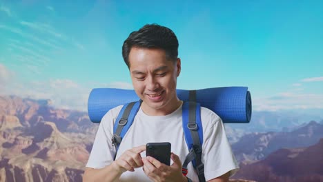 close up of asian male hiker with mountaineering backpack enjoy using smartphone while traveling at the top of mountain