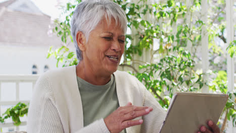 Senior-mixed-race-woman-having-video-chat-using-tablet-in-garden