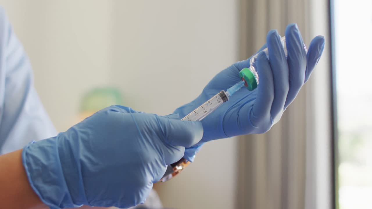 video de las manos de una doctora biracial preparando una vacuna