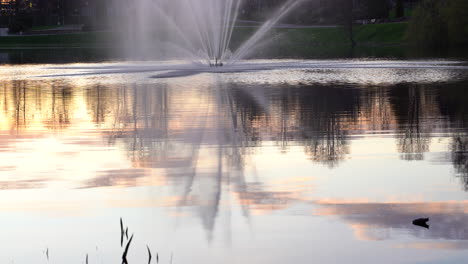 Evening-reflection-of-fountain-in-Dzirnavu-ezeriņš-at-park-in-Valmiera,-Latvia