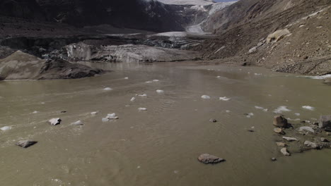 Drohnenaufnahme-Von-Totem-Pasterze-Gletscherseewasser-Mit-Schwimmendem-Eisberg,-Strom-Aus-Schlammigem-Gletscherwasser