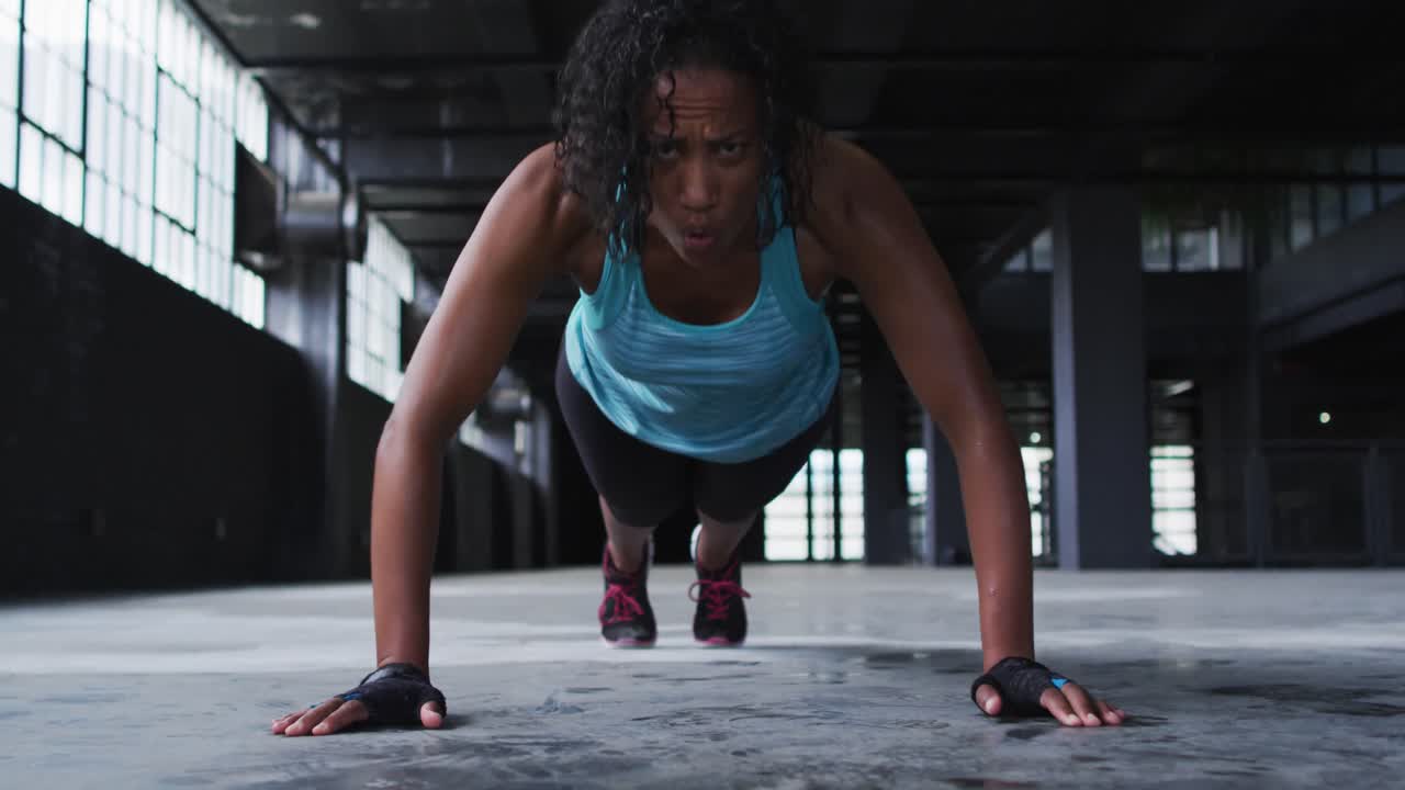 African american woman doing push ups in an empty urban building