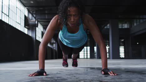 african american woman doing push ups in an empty urban building