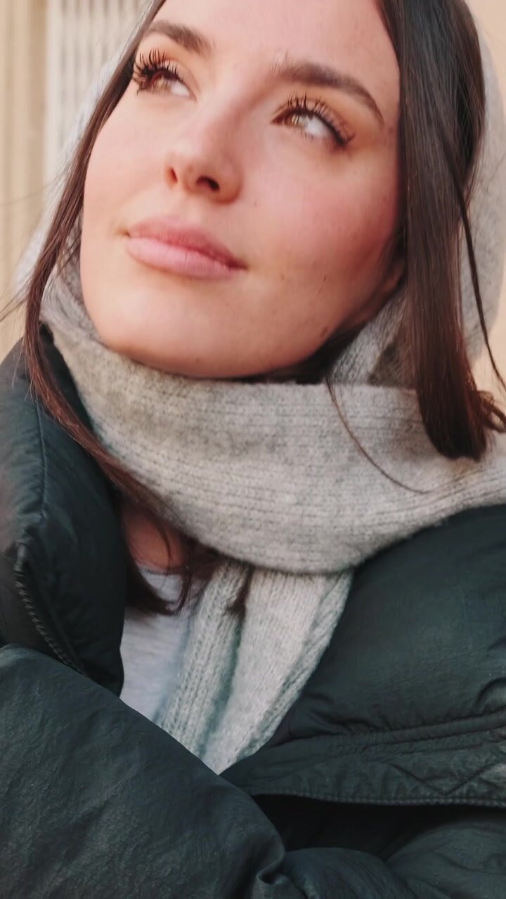 Giovane donna con abbigliamento invernale che guarda verso l'alto all'aperto