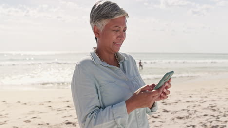 Phone,-relax-and-senior-woman-at-beach-for-text