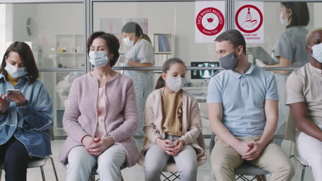 diverse people in masks waiting in hospital queue